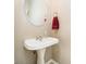 Cozy powder room featuring a pedestal sink, decorative mirror, and wall-mounted towel ring with a red towel at 5698 Kenderly Ct, Carmel, IN 46033