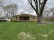 Inviting brick home boasts a lovely front porch, complemented by lush green lawn and mature trees, offering curb appeal at 5774 N Ewing St, Indianapolis, IN 46220