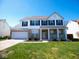 Charming two-story home with a well-manicured lawn, brick accents, and a welcoming front porch with white pillars at 7150 Pheasant Ridge Dr, Indianapolis, IN 46237