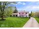 Charming two-story home with a long driveway, large yard, mature trees, and manicured flower beds at 7440 Graham Rd, Indianapolis, IN 46250