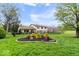 Attractive landscaping, including an island of bushes, flowers, and mulch, highlight this home's yard at 7440 Graham Rd, Indianapolis, IN 46250