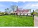 A home's manicured lawn, mature landscaping, and decorative flowering tree offer great curb appeal at 7440 Graham Rd, Indianapolis, IN 46250