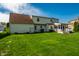 Spacious backyard features a large green lawn, a two-story house, and blue sky with fluffy clouds at 8142 Bittern Ln, Indianapolis, IN 46256