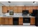 Kitchen with sleek black appliances and warm wood cabinetry at 8410 Glenwillow Ln # 208, Indianapolis, IN 46278