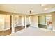 Open living space with carpet flooring, ceiling fan, staircase, and access to kitchen at 8830 Kipling Dr, Indianapolis, IN 46239