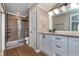 Well-lit bathroom showcasing a shower with a glass enclosure, a white vanity and wood-look floors at 9162 Cinnebar Dr, Indianapolis, IN 46268