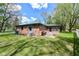 Spacious backyard with lush green grass, brick home, patio area, and partial white fence at 1101 Oakwood Trl, Indianapolis, IN 46260