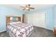 Bright bedroom features soft blue walls, plush carpet, ceiling fan, and a mirrored headboard at 1101 Oakwood Trl, Indianapolis, IN 46260