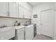 Well-lit laundry room with white cabinets, subway tile backsplash, and modern washer and dryer units at 1295 Clairet Dr, Westfield, IN 46074