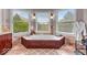 Bright bathroom featuring a large garden tub, tile surround, and three windows that provide natural light and a scenic view at 1510 Central Ave, Indianapolis, IN 46202