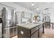 Open kitchen with stainless steel refrigerator, granite island, and modern pendant lighting fixture at 16726 Blackbird Ct, Noblesville, IN 46060