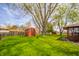 Beautiful backyard featuring green grass, mature trees, and storage sheds at 1908 Roundhill Dr, Anderson, IN 46013