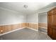 Bedroom with gray floors, light walls, wainscoting detail and wood door at 1908 Roundhill Dr, Anderson, IN 46013