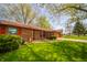Charming brick home showcasing vibrant green lawn, mature trees, and a well-maintained landscape at 1908 Roundhill Dr, Anderson, IN 46013