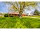 Beautiful brick home featuring a spacious front yard with mature trees and a serene setting at 1908 Roundhill Dr, Anderson, IN 46013