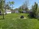Lush backyard featuring a fire pit, mature trees, and a well-maintained lawn, great for outdoor living at 2143 N Graham Ave, Indianapolis, IN 46218