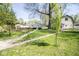 The expansive backyard includes a grass lawn, two pathways, mature trees, and a view of detached buildings at 233 N Fenton Ave, Indianapolis, IN 46219