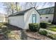 Exterior view of the detached garage with a green trim, bushes surrounding it, and a peek at the backyard at 233 N Fenton Ave, Indianapolis, IN 46219