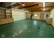 A large garage interior featuring built-in shelves, cabinets, a partially constructed staircase, and a striking green floor at 233 N Fenton Ave, Indianapolis, IN 46219
