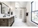 Modern bathroom featuring a double vanity, bathtub with shower, subway tile, and a window at 3868 N Park Ave, Indianapolis, IN 46205