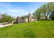 Side view of the home with manicured lawn, stone chimney, and mature trees at 5079 S Lick Creek Rd, Morgantown, IN 46160