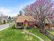 Charming brick home with a cozy front porch, green lawn and a beautiful pink blooming tree at 5697 Broadway St, Indianapolis, IN 46220