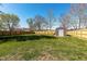 A large, grassy backyard surrounded by a wood fence and featuring a storage shed at 598 Collier St, Columbus, IN 47201