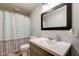 A well lit bathroom features a single sink vanity, large mirror and shower with curtain at 598 Collier St, Columbus, IN 47201