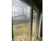 View of the fenced backyard through the window with trees and a fire pit at 6011 Mcclellan Ct, Indianapolis, IN 46254
