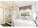 Bathroom offers walk-in glass shower and soaking tub under a window at 6164 Parrington Dr, Indianapolis, IN 46236