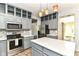Updated kitchen features an island, stainless appliances, grey cabinets, and tiled flooring at 6164 Parrington Dr, Indianapolis, IN 46236