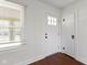 Entryway with white door, wood floors, window with blinds, and white walls at 6307 Broadway St, Indianapolis, IN 46220