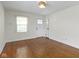Living room with white door, hardwood floors, window with blinds, and white walls at 6307 Broadway St, Indianapolis, IN 46220
