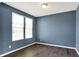 This blue bedroom features wood floors, neutral trim, and a large window at 6827 Fallen Leaf Dr, Whitestown, IN 46075