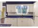 Well-lit kitchen with white cabinetry, blue countertops, and stainless steel dishwasher at 11 Woodacre Dr, Carmel, IN 46032