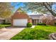 Attractive brick home with a two-car garage, blooming trees, and a well-kept lawn, creating a welcoming entrance at 1127 Alydar Cir, Indianapolis, IN 46217