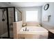 Bathroom featuring a tiled tub, black hardware, glass shower door, with a window bringing in natural light at 11592 Saltford Ln, Fishers, IN 46037