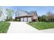 Three-car garage with a paved driveway and well-kept landscaping around the perimeter at 11592 Saltford Ln, Fishers, IN 46037