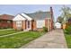 Cozy home featuring a well-kept lawn, traditional brickwork, and a detached garage with a private driveway at 1209 N Downey Ave, Indianapolis, IN 46219