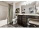 Well-lit bathroom features a vanity with dark wood cabinets, a tub with shower, and decorative shelving at 12210 Doncaster Ct, Fishers, IN 46037