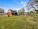 Spacious backyard with a large red barn, greenhouse, and fenced-in area, ideal for outdoor activities and hobbies at 1394 N Michigan Rd, Shelbyville, IN 46176