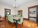 Dining room with hardwood floors, featuring a weathered wood table and green upholstered chairs, adjacent to connecting rooms at 1394 N Michigan Rd, Shelbyville, IN 46176
