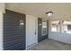 A well lit covered porch features gray siding, concrete flooring, modern wall fixtures, and a white front door at 1627 Lawton Ave, Indianapolis, IN 46203