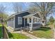 This home features gray siding, a covered porch with white accents, a chain-link fence, and a well-maintained lawn at 1627 Lawton Ave, Indianapolis, IN 46203