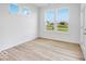 Minimalist bedroom with light wood flooring, white walls, and a view of the backyard through three windows at 2257 Aviary Ln, Danville, IN 46122