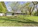 Large backyard featuring a home with big sliding glass doors, mature trees, and a grassy area at 2325 Melody Ln, Anderson, IN 46012