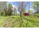 Expansive backyard featuring a large grassy area, mature trees, and a charming red barn at 2325 Melody Ln, Anderson, IN 46012