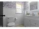 Charming bathroom with floral wallpaper, a white vanity, and wainscoting at 2325 Melody Ln, Anderson, IN 46012