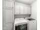 This laundry room features white cabinets and a front load washer and dryer at 3582 Fieldhurst Ln, Plainfield, IN 46168