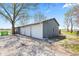 Exterior view of a three-bay garage with white doors surrounded by a gravel and grass landscape at 4155 S State Rd 39, Lebanon, IN 46052